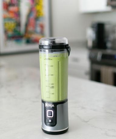 Portrétny záber prenosného mixéra Ninja Blast v kuchyni Heather Biens na bielej mramorovej pracovnej doske so zeleným smoothie nápojom