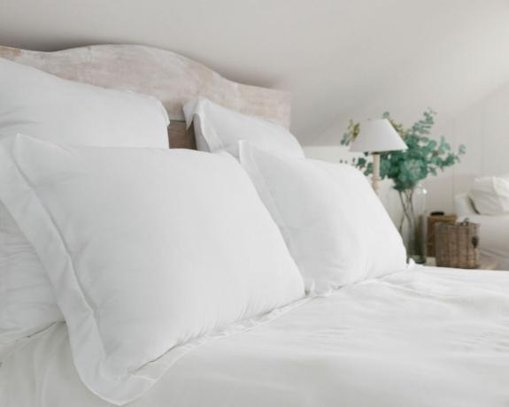 weiße Kissen und Bettwäsche mit Kopfteil aus Holz